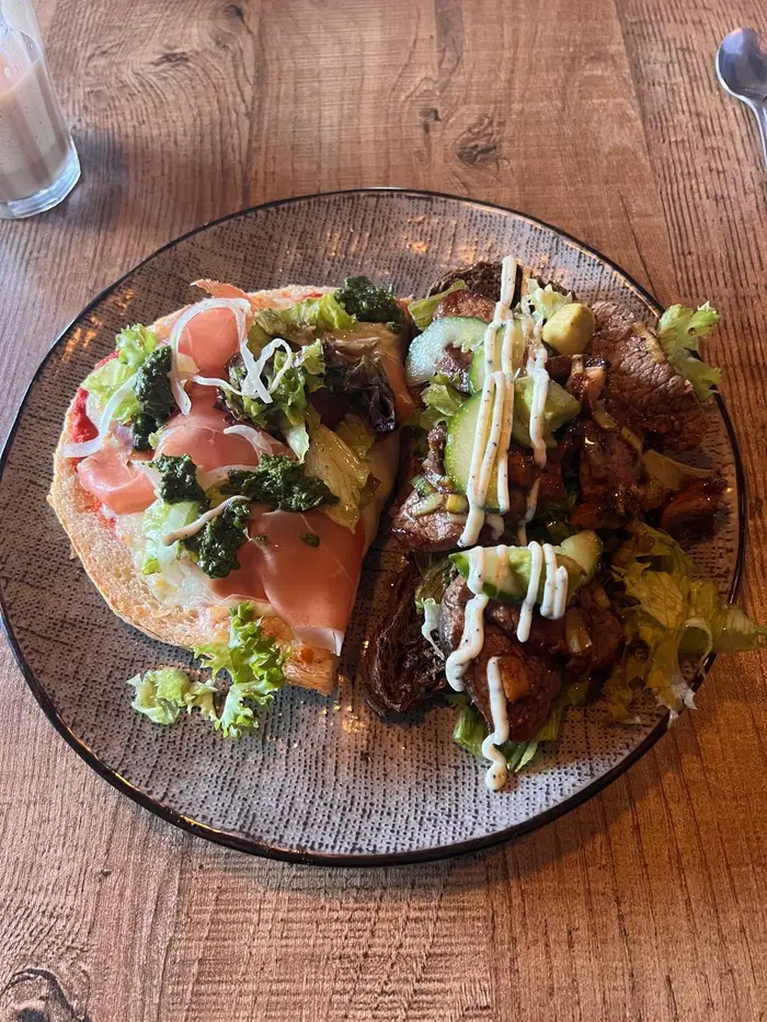 Een bord met een open broodje met ham en pesto en een broodje met vlees, komkommer en saus