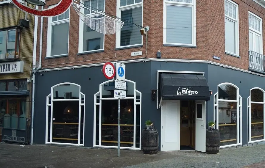 De gevel van La Bistro: antraciet met witte boogramen en een zwarte luifel met het logo